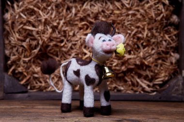 Ahşap arka planda pelüş boğa oyuncağı. Yumuşak bir oyuncak izleyiciyi selamlar. 2021 Yeni Yıl Sembolü.