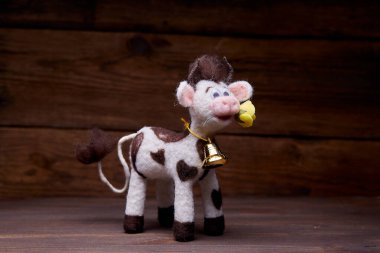 Ahşap arka planda pelüş boğa oyuncağı. Yumuşak bir oyuncak izleyiciyi selamlar. 2021 Yeni Yıl Sembolü.