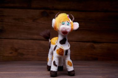 Ahşap arka planda pelüş boğa oyuncağı. Yumuşak bir oyuncak izleyiciyi selamlar. 2021 Yeni Yıl Sembolü.