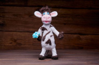 Ahşap arka planda pelüş boğa oyuncağı. Yumuşak bir oyuncak izleyiciyi selamlar. 2021 Yeni Yıl Sembolü.