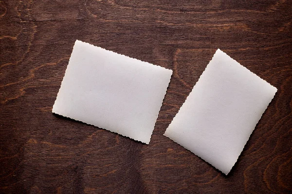 Mockup av vintage vit papper lista vid texturerat trä bord bakgrund. — Stockfoto