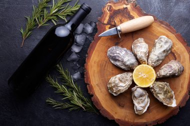 Taze kapalı istiridye, yuvarlak tabakta buz ve limon, taş desenli arka plan..