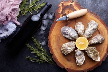 Taze kapalı istiridye, yuvarlak tabakta buz ve limon, taş desenli arka plan..
