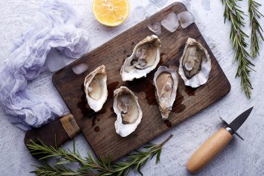 Taze açılmış istiridye, buz ve limon yuvarlak tabakta, taş desenli arka planda..