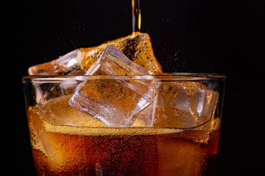 Köpüklü köpüklü kola ferahlatıcı buzlu gazoz. Siyah arkaplanda bir bardak kola..