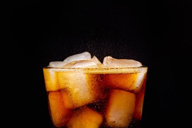 Köpüklü köpüklü kola ferahlatıcı buzlu gazoz. Siyah arkaplanda bir bardak kola..
