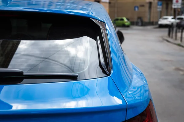 Back window of blue car parked on the street in summer sunny day, rear view. Mock-up for sticker or decals