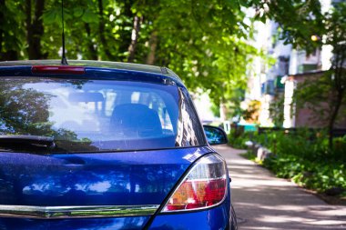 Yazın güneşli bir günde, arka pencereye park edilmiş mavi bir araba. Çıkartma veya çıkartma için modelleme