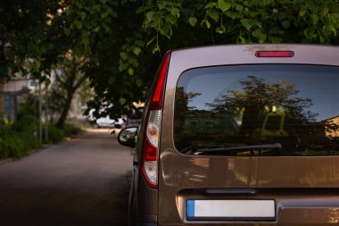 Bronz arabanın arka camı yaz güneşli bir günde caddeye park edilmiş, dikiz manzaralı. Çıkartma veya çıkartma için modelleme