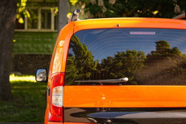 Turuncu arabanın arka penceresi yaz güneşli bir günde, dikiz manzaralı caddeye park edilmiş. Çıkartma veya çıkartma için modelleme