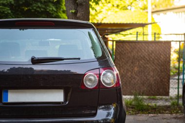 Yazın güneşli bir günde, arka pencereye park edilmiş siyah bir araba. Çıkartma veya çıkartma için modelleme