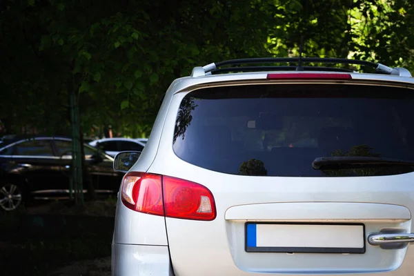 Back window of white car parked on the street in summer sunny day, rear view. Mock-up for sticker or decals