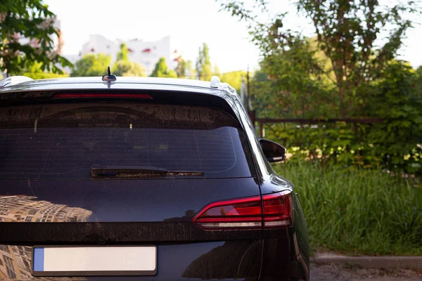 Back window of black car parked on the street in summer sunny day, rear view. Mock-up for sticker or decals