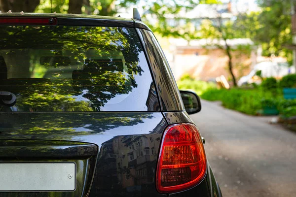 Rückscheibe eines schwarzen Autos, das an einem sonnigen Sommertag auf der Straße geparkt war, Rückansicht. Mock-up für Aufkleber oder Abziehbilder — Stockfoto