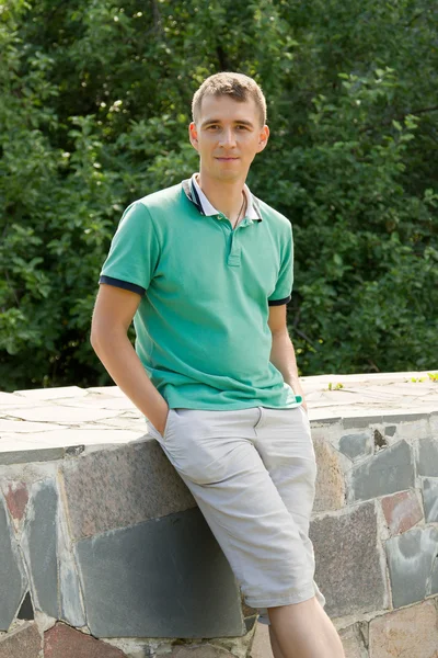 Portrait of attractive young man leaning against a stone parapet — Stock Photo, Image