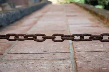 Asfalt sokaktaki paslı zincirin yakın çekim görüntüsü.