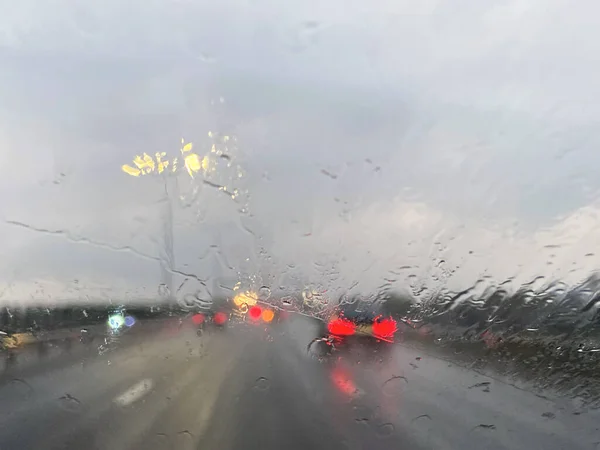 Highway traffic in heavy rain seen through wet windshield