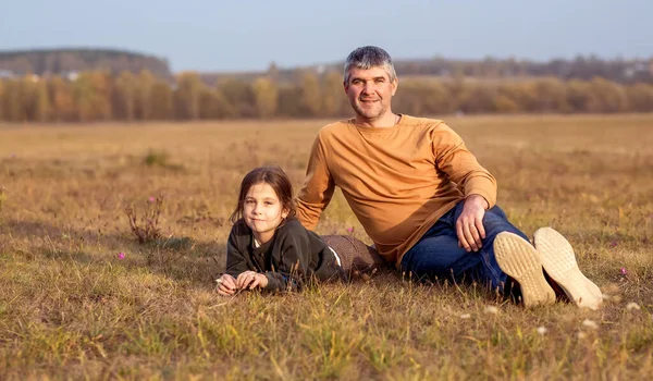 Padre e hija sentados en la hierba en un campo al atardecer. — Foto de Stock