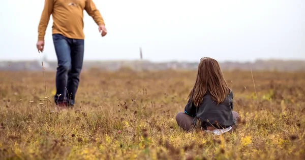 Отец и дочь сидят на траве в поле на закате. — стоковое фото