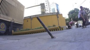 Genç bir beyaz adam otoparkta paten kayıyor.