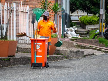 Medellin, Antioquia / Kolombiya - 20 Kasım 2020: Turuncu Üniformalı Çöpçü Çöp Kutusu Taşıyor