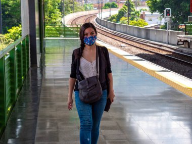 Latin Kadın metro istasyonunda maske takıyor ve yürüyor.