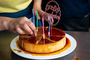 Doğum günü pastasından renkli mumları çeken kadın elleri.