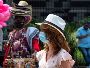 Medellin, Antioquia, Kolombiya - 6 Ocak 2021: Maske Giyen Turist Bir Satıcıdan Şapka Deniyor.