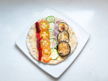 Humus, domates dilimleri, salatalık, patlıcan, pancar ve kırmızı soğanla servis edilen Lübnan sandviçi.