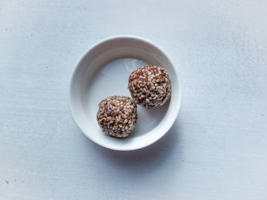 Kakaolu yulaf ezmesi topları, fıstık ezmesi, akçaağaç şurubu ve beyaz arka planda susam tohumu.