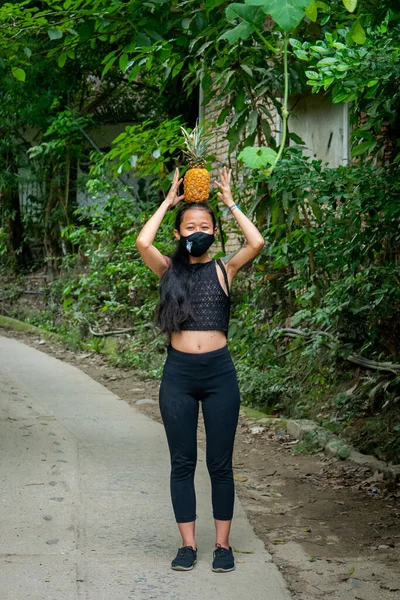 Ağzında Kara Maskeli Asyalı Kadın Kafasında Bir Ananas Tutuyor — Stok fotoğraf
