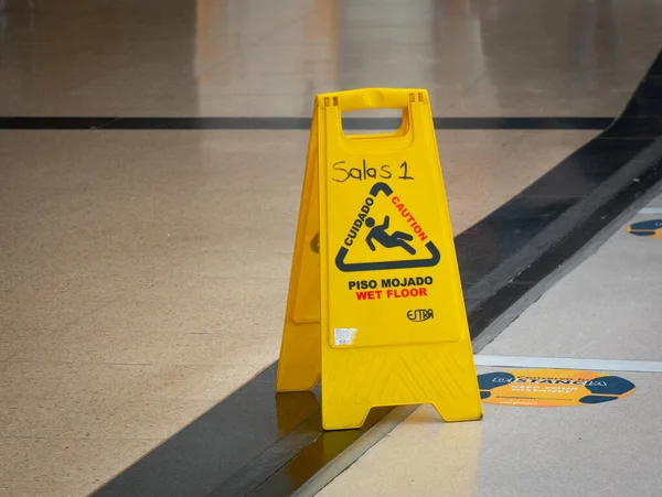 Yellow Wet Floor Warning Tool Written in English and Spanish at the Airport (Rooms 1 - Caution - Wet Floor -  Keep your Distance)