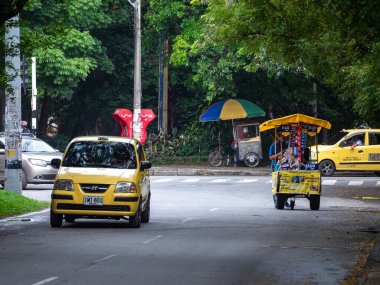 Medellin, Antioquia, Kolombiya - 24 Temmuz 2021: Bulutlu bir günde taksiler ve sokak satıcıları