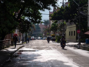 Medellin, Kolombiya - 30 Temmuz 2021: Küçük Trafikli Sokak, Kenarlarında Ağaçlar ve Güneşli Bir Gün 'de Yürüyen İnsanlar