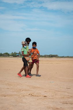 Riohacha, La Guajira, Kolombiya - 30 Mayıs 2021: Genç Yerli Latin Erkekler Camarones Denizi yakınlarındaki Arid Çölü 'nde Yürüyorlar