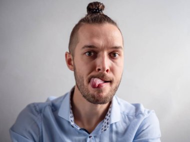 Beyaz genç adam, dili ağzında komik görünüyor.