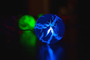 Karanlık bir odada parlayan mavi bir çelenk topu.