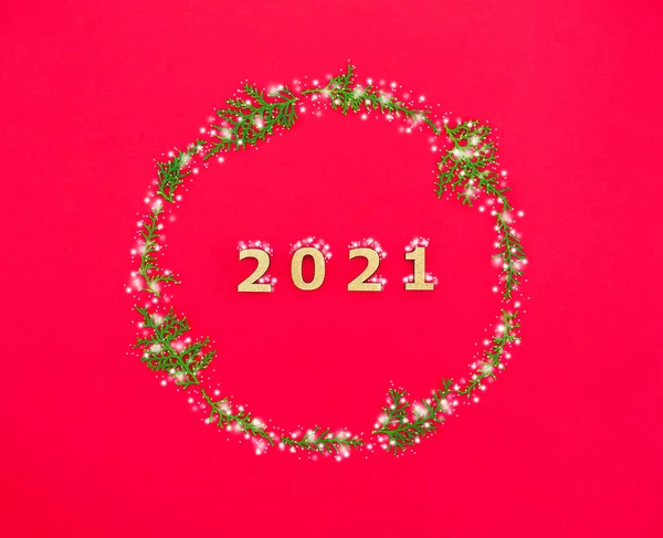 2021 yazısıyla yeni yıl kompozisyonu ve kırmızı zemin üzerinde kar kaplı kozalaklı dallar..