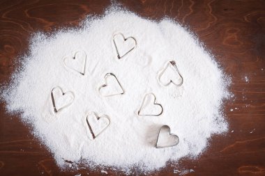 Kahverengi ahşap bir masada un üzerinde küçük kalpler