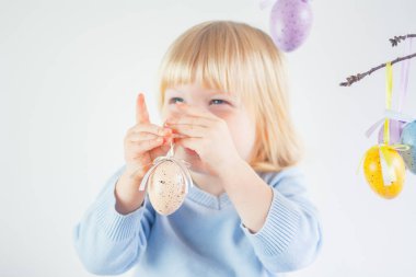 Elinde dekoratif Paskalya yumurtası tutan neşeli sarışın çocuk.