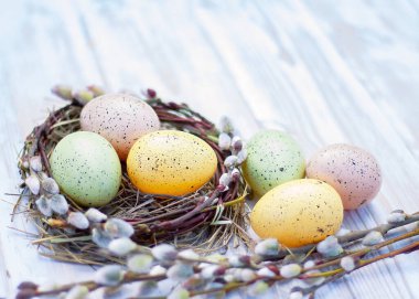 Beyaz tahtalarda çiçek açan söğüt dalları ve renkli Paskalya yumurtaları.