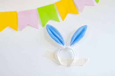 Süslü paskalya tavşanı kulakları beyaz bir duvara bantlanmış bayrakların yanında.