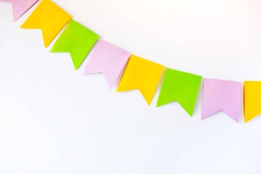 Beyaz duvarda renkli kağıt bayrakların olduğu renkli bir çelenk.