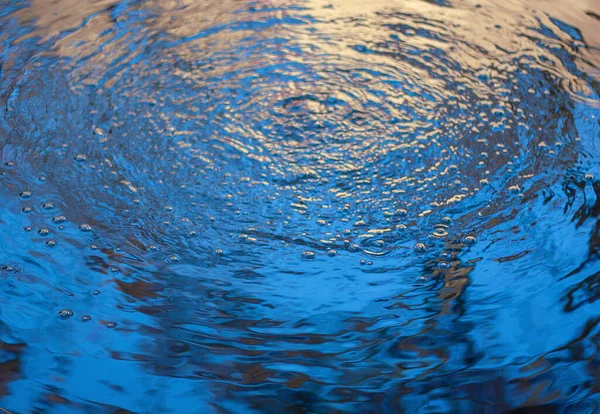 water surface with circles and splashes and light reflection. natural water background