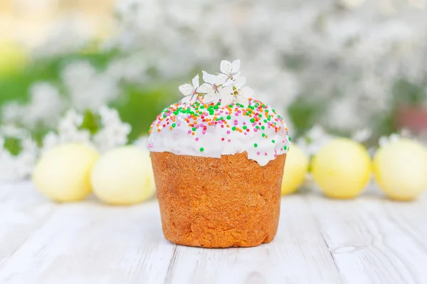 Tatlı Paskalya pastası - Paska, kulich, çiçeklerle süslenmiş, çiçek açan bir bahar bahçesinde.