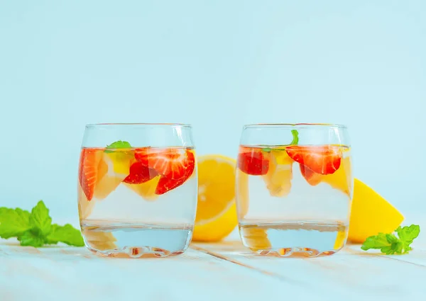 two glasses with a refreshing summer beverage made from lemon, strawberry and mint. lemonade water. citrus and berry cocktail.