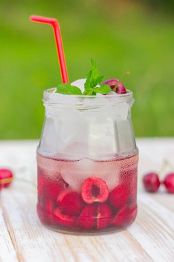 Bahçedeki masanın üzerinde vişne ferahlatıcı bir içecek. Buzlu yaz kokteyli. Detoks suyu