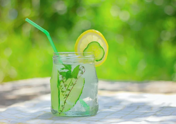 infused cucumber detox water with ice. refreshing summer drink on the table in the garden.