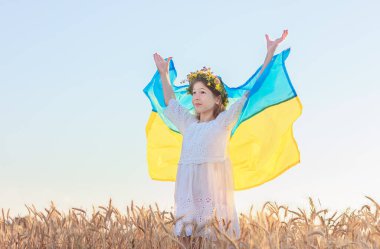 Buğday tarlasında gökyüzünün arka planında sevimli bir kız ve Ukrayna bayrağı. Ukrayna 'nın ulusal bağımsızlığının mavi ve sarı sembolü.
