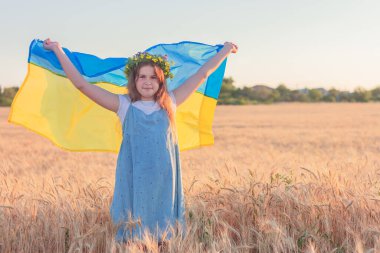 Kopya alanı olan buğday tarlasında mavi-sarı Ukrayna bayrağı olan tatlı bir kız. Ukrayna 'nın bağımsızlık günü, anayasa günü, bayrak günü.